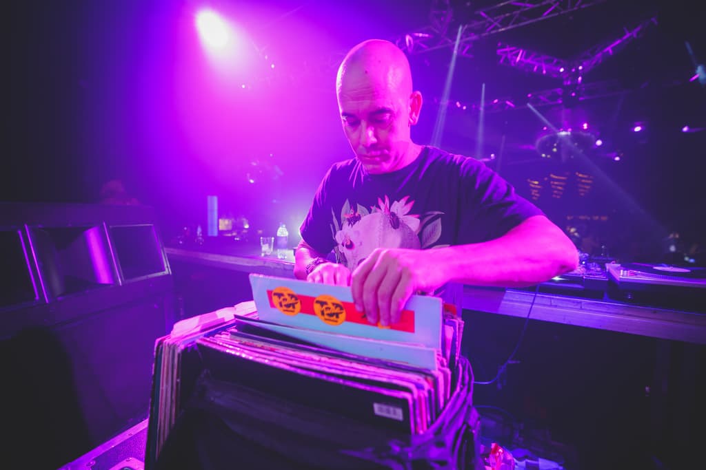 El DJ elige un vinilo en la cabina bajo luz morada