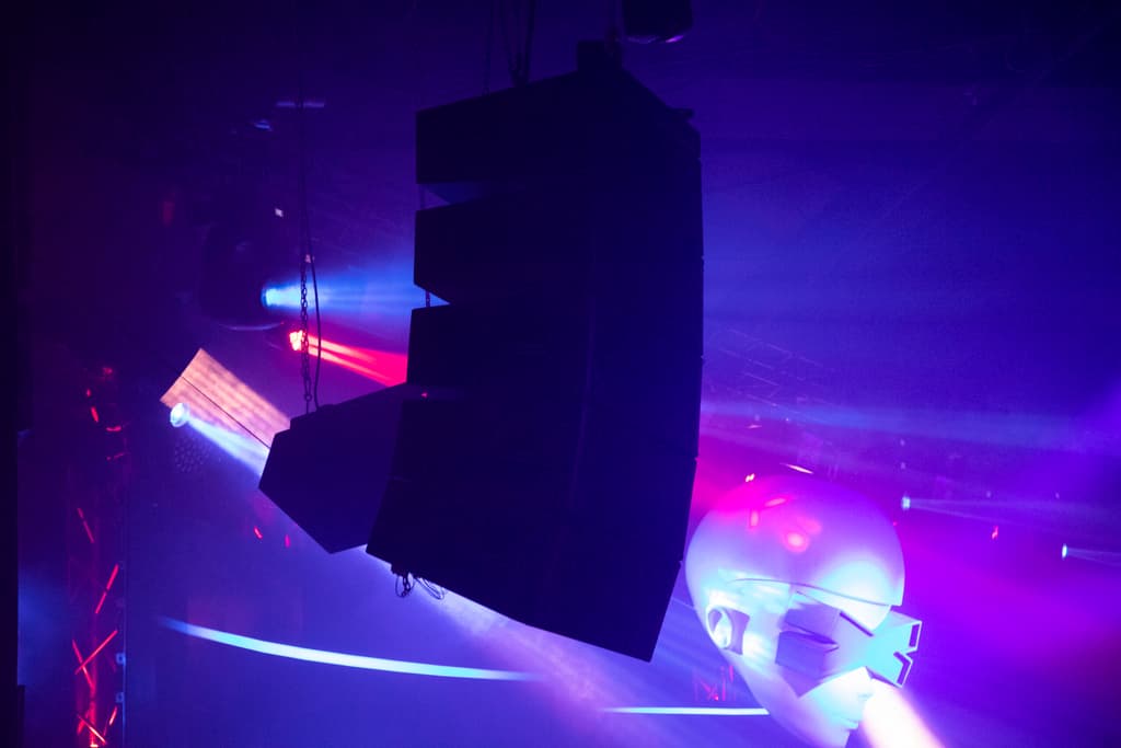 Altavoces line array suspendidos sobre la pista entre focos de colores